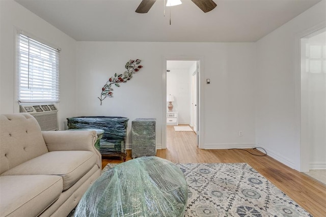 living room with light wood-style flooring, baseboards, ceiling fan, and cooling unit