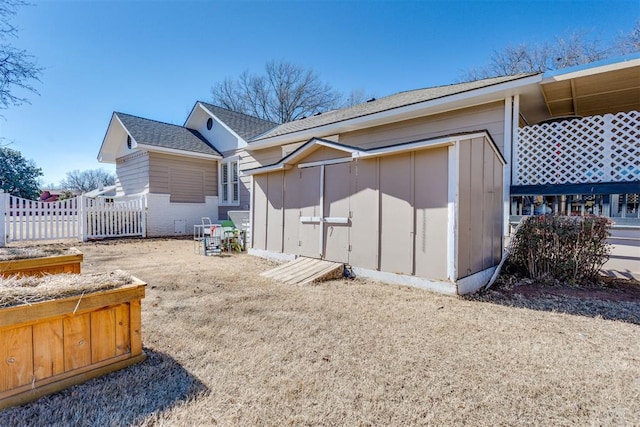 rear view of house featuring fence, an outdoor structure, and a storage shed