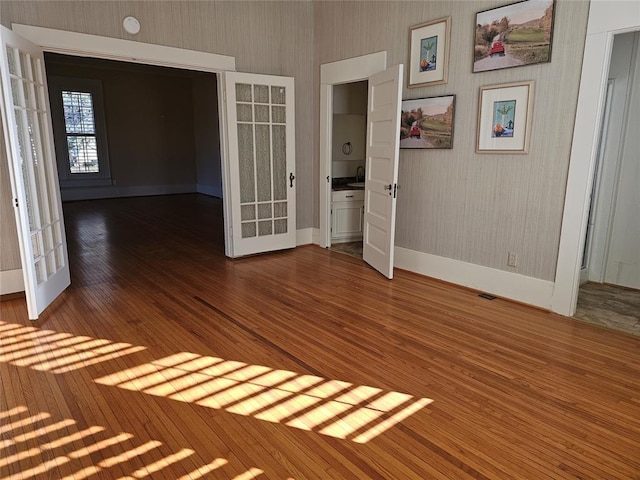 804 N Willow St, Pauls Valley, OK 73075 - empty room with wallpapered walls, french doors, and hardwood / wood-style floors