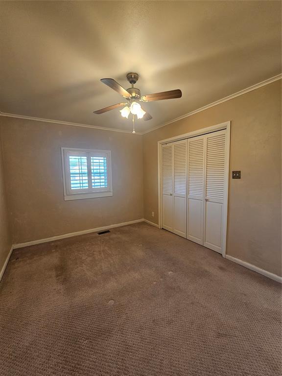 804 N Willow St, Pauls Valley, OK 73075 - unfurnished bedroom featuring baseboards, a closet, crown molding, and carpet flooring