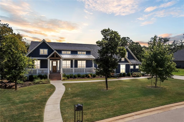 view of front of home with a standing seam roof, metal roof, a front lawn, and covered porch