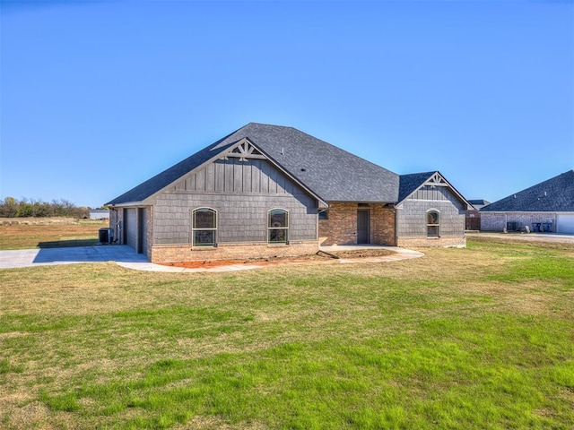 view of front of property with a shingled roof, a front lawn, and brick siding