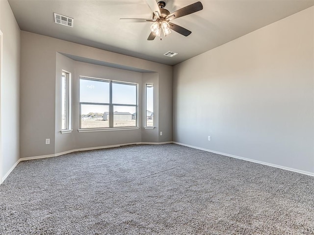 carpeted empty room featuring baseboards, visible vents, and ceiling fan