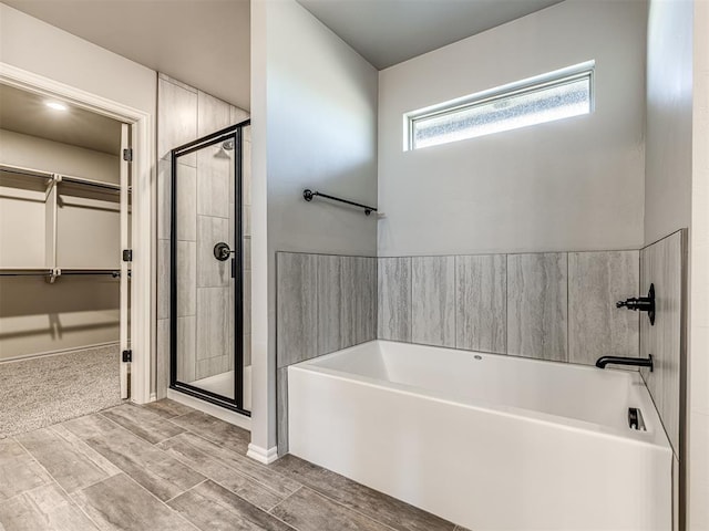 bathroom featuring a stall shower, a walk in closet, and a bath