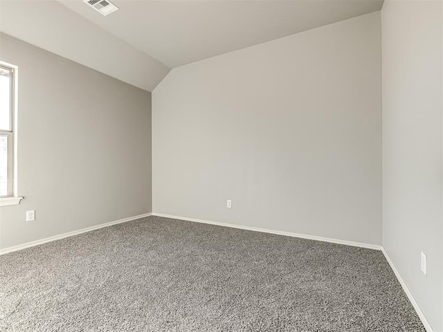 carpeted empty room featuring vaulted ceiling, visible vents, and baseboards