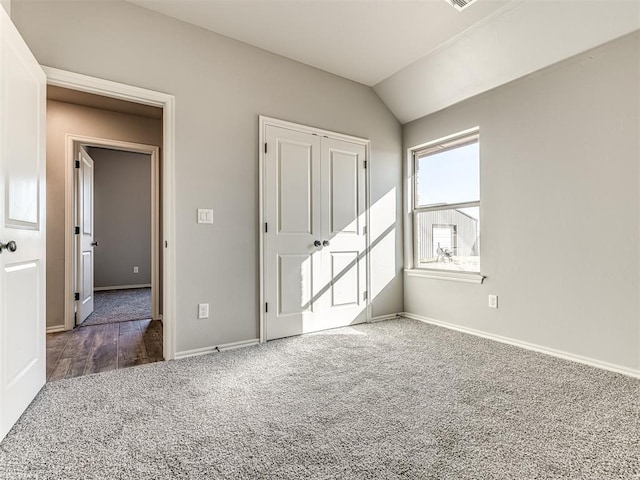 unfurnished bedroom featuring carpet floors, vaulted ceiling, and baseboards