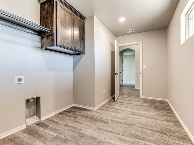 washroom with cabinet space, arched walkways, light wood finished floors, and hookup for an electric dryer