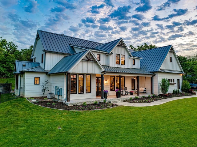 rear view of property with a standing seam roof, a lawn, and a patio