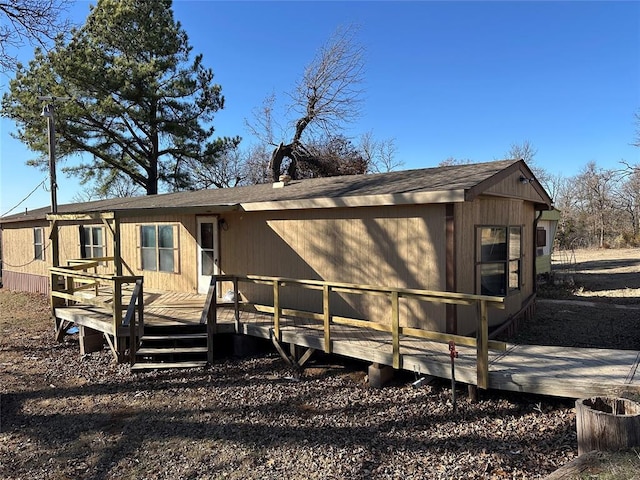 rear view of property featuring roof with shingles and a deck