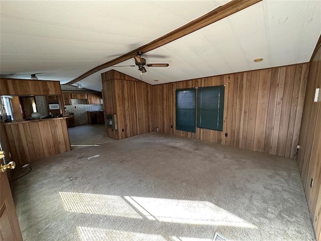 unfurnished living room with carpet, vaulted ceiling with beams, wood walls, and ceiling fan