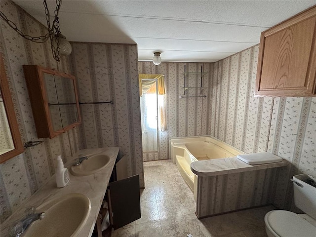 bathroom featuring a sink, a tub, and wallpapered walls