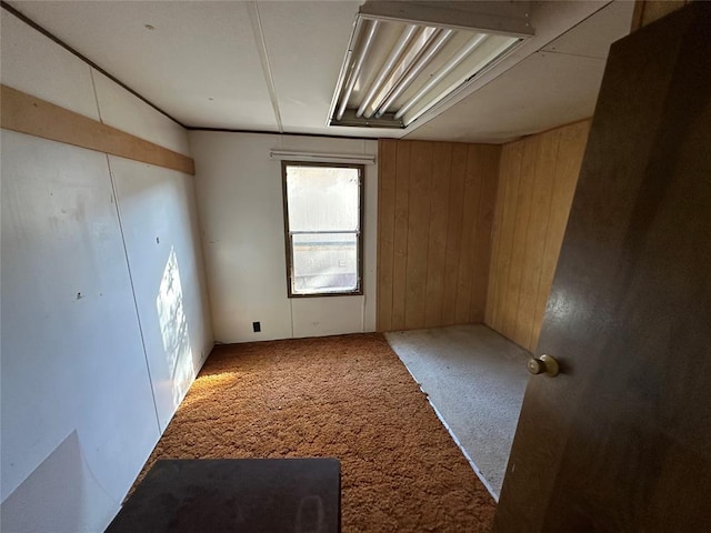 empty room featuring carpet floors and wooden walls