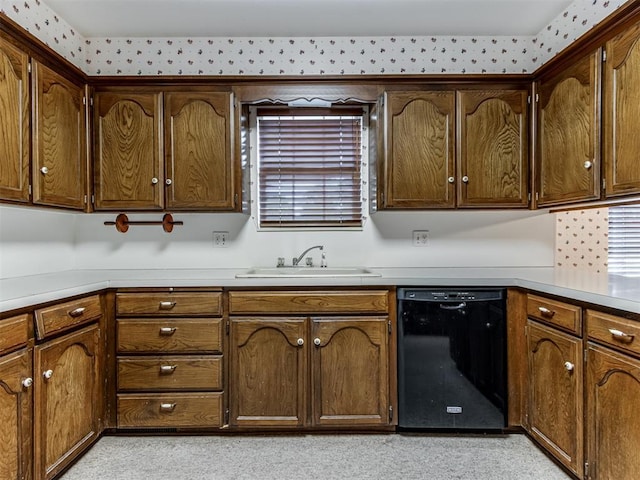 kitchen featuring black dishwasher, light countertops, and a sink