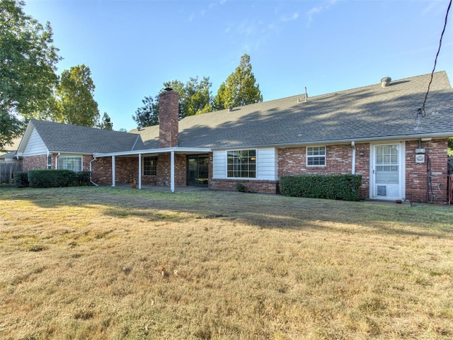 view of front facade with roof with shingles, a chimney, a front lawn, and brick siding