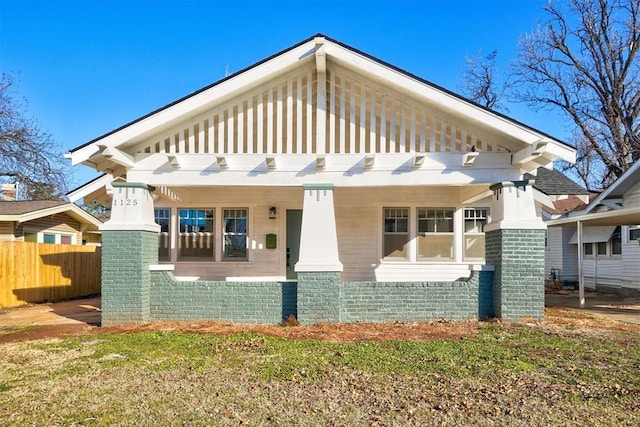 view of front facade featuring fence, a porch, and brick siding