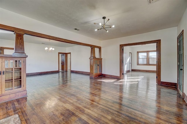 unfurnished living room with visible vents, baseboards, a notable chandelier, and wood finished floors