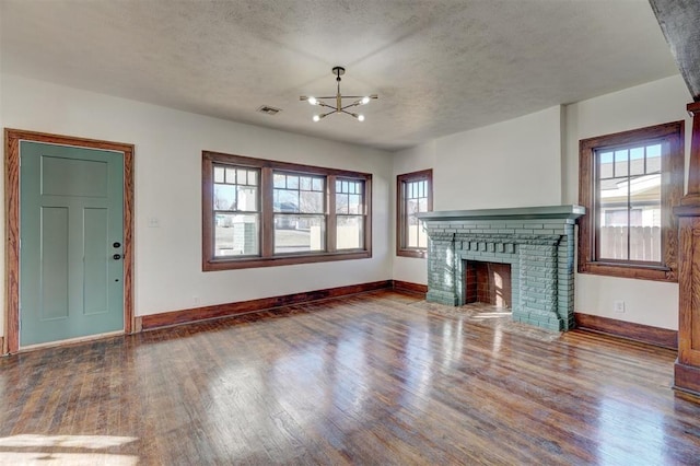 unfurnished living room featuring baseboards, a brick fireplace, wood finished floors, and a healthy amount of sunlight