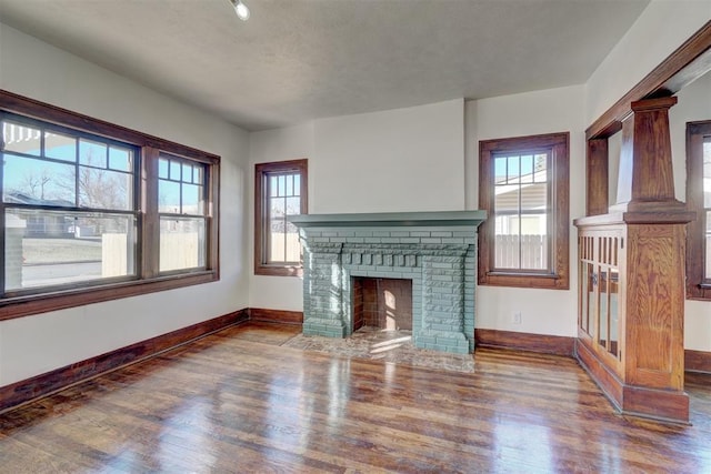 unfurnished living room featuring plenty of natural light, baseboards, and wood finished floors