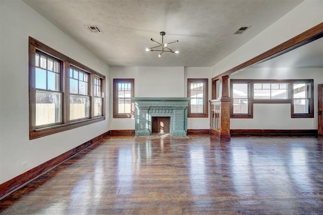 unfurnished living room featuring a fireplace, wood finished floors, visible vents, and baseboards