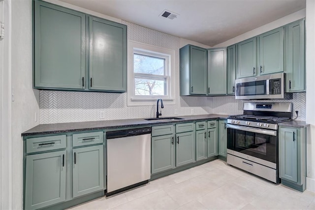 kitchen with appliances with stainless steel finishes, visible vents, a sink, and green cabinetry