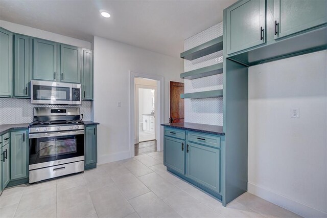 kitchen with light tile patterned flooring, stainless steel appliances, baseboards, open shelves, and tasteful backsplash