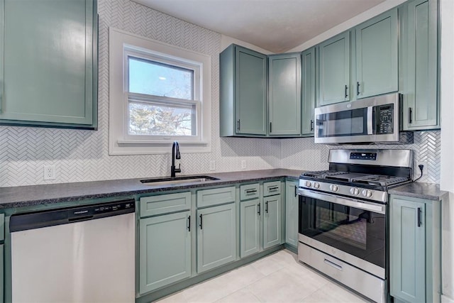 kitchen featuring a sink, stainless steel appliances, green cabinets, backsplash, and light tile patterned flooring