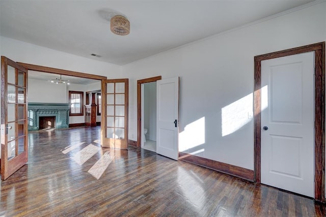 foyer entrance featuring a fireplace, wood finished floors, visible vents, baseboards, and french doors