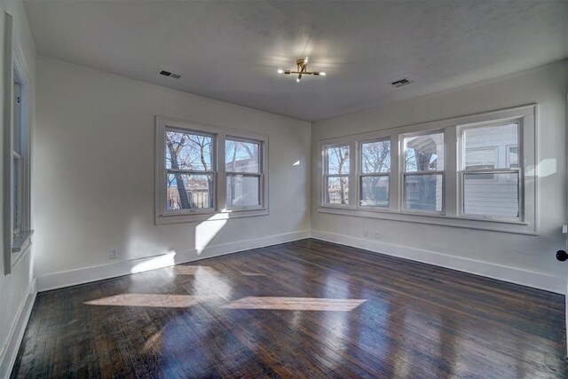 spare room featuring baseboards, visible vents, and dark wood-type flooring