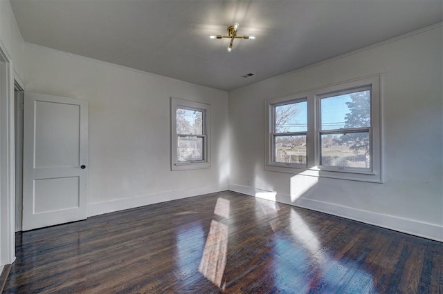 empty room featuring ornamental molding, dark wood finished floors, visible vents, and baseboards