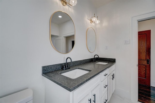 bathroom with marble finish floor, a sink, toilet, and double vanity