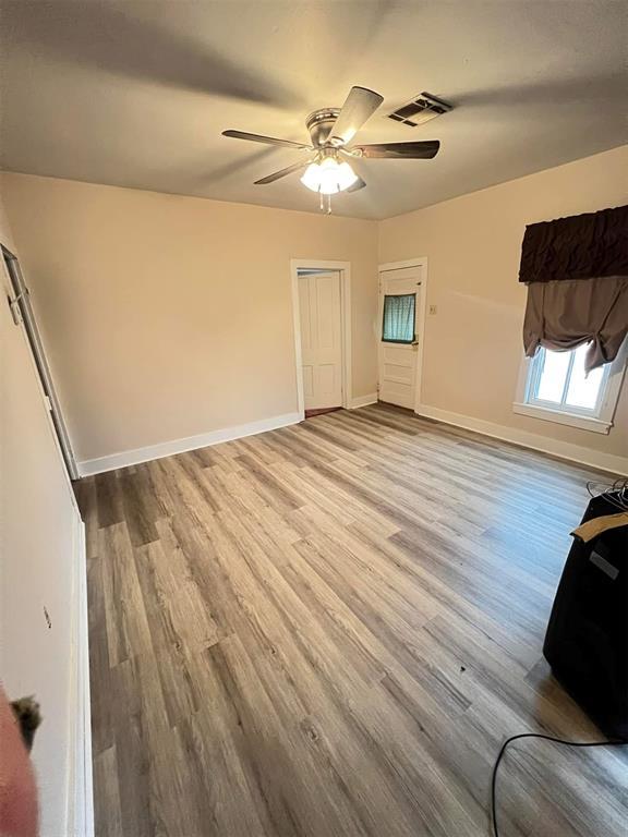 unfurnished bedroom with a ceiling fan, visible vents, baseboards, and wood finished floors