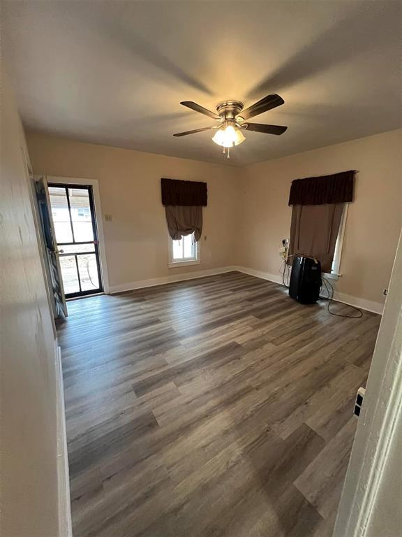 unfurnished room with a ceiling fan, baseboards, and wood finished floors