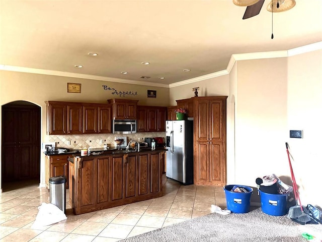 kitchen with tasteful backsplash, dark countertops, an island with sink, appliances with stainless steel finishes, and light tile patterned flooring