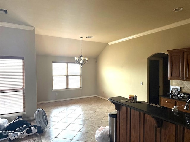 kitchen with light tile patterned floors, arched walkways, vaulted ceiling, decorative backsplash, and dark countertops