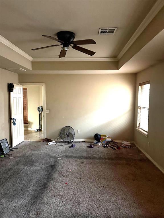 unfurnished room featuring baseboards, visible vents, a tray ceiling, crown molding, and carpet flooring