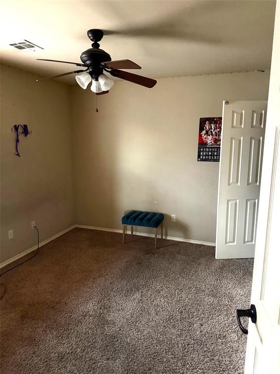 empty room featuring carpet floors, visible vents, baseboards, and a ceiling fan