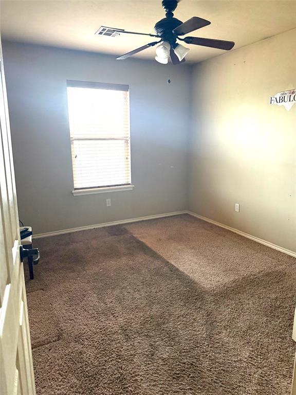 carpeted spare room featuring ceiling fan and baseboards