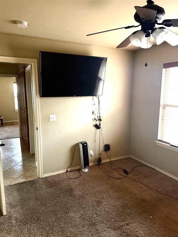 unfurnished living room featuring light tile patterned floors, baseboards, a ceiling fan, and light colored carpet