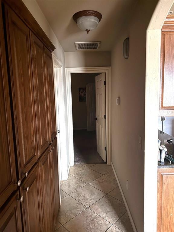 corridor featuring visible vents, baseboards, and light tile patterned floors