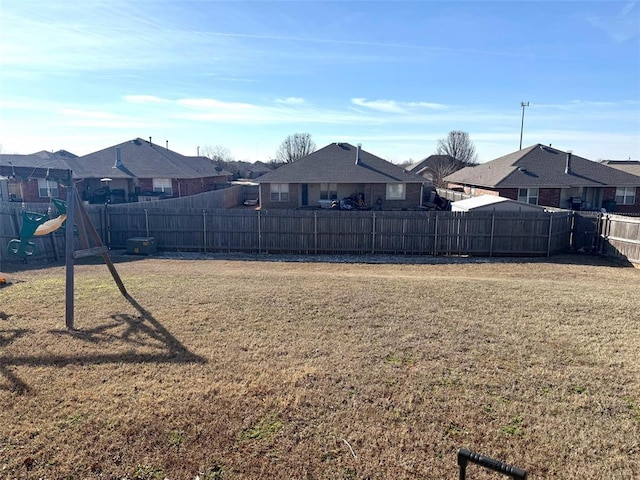 view of yard featuring a fenced backyard, a residential view, and a playground