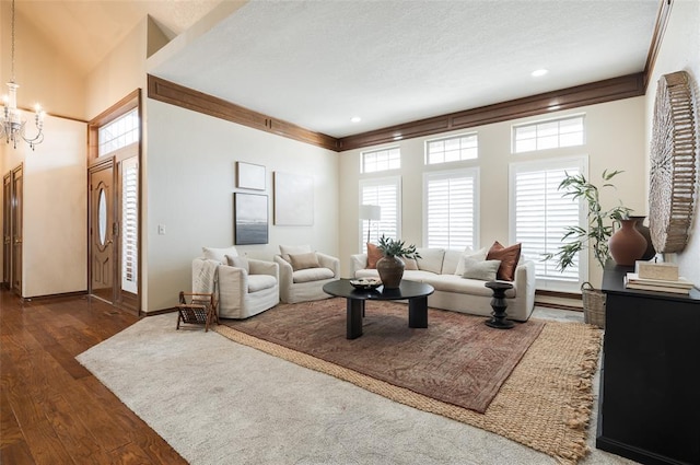 living room with a notable chandelier, baseboards, dark wood-style flooring, and ornamental molding