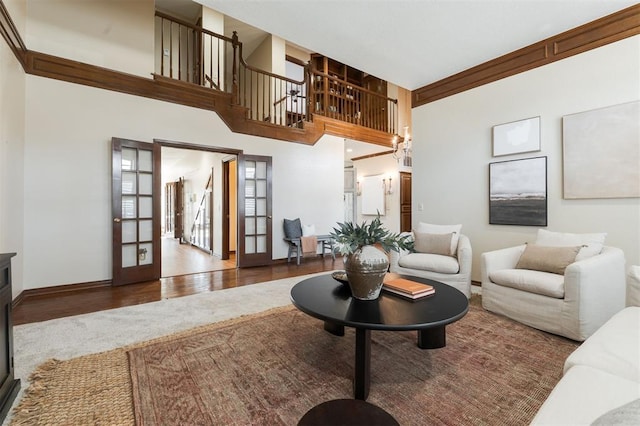 living room with french doors, baseboards, a high ceiling, and wood finished floors