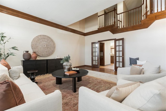 living area featuring french doors, a towering ceiling, and wood finished floors