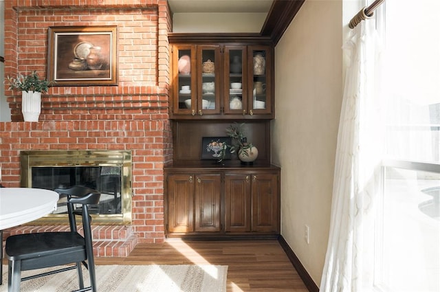 interior space with a brick fireplace, wood finished floors, and baseboards