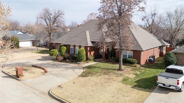 view of front of property with a front yard, cooling unit, concrete driveway, and brick siding