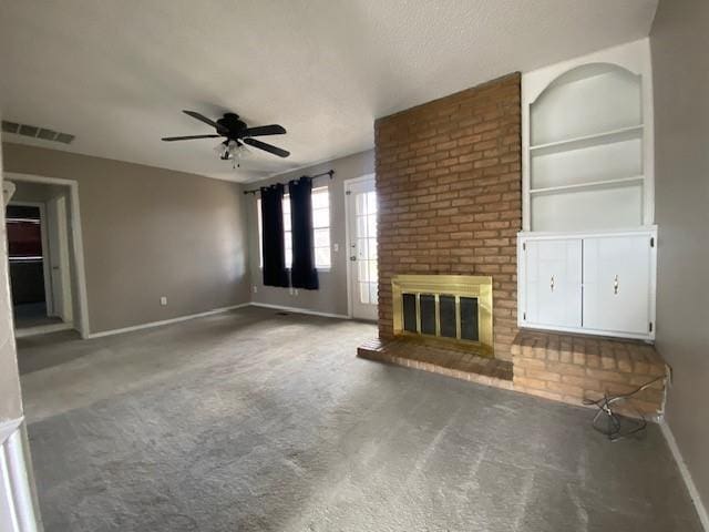 unfurnished living room featuring visible vents, built in shelves, baseboards, a brick fireplace, and ceiling fan