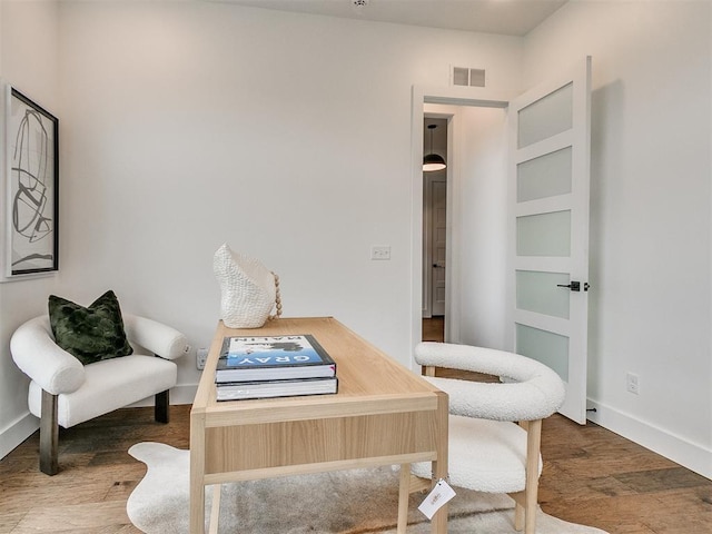 living area with visible vents, baseboards, and wood finished floors