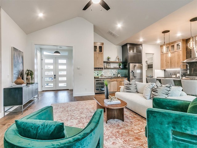 living room with wine cooler, french doors, visible vents, vaulted ceiling, and wood finished floors