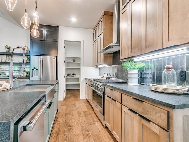 kitchen featuring light wood-style flooring, appliances with stainless steel finishes, wall chimney exhaust hood, tasteful backsplash, and glass insert cabinets