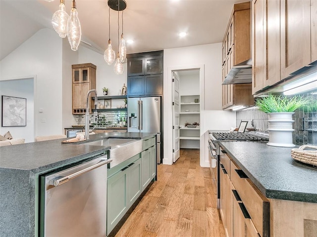 kitchen with appliances with stainless steel finishes, dark countertops, light wood-style floors, and under cabinet range hood